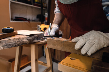 Close up hand of carpenter using square angle ruler tool and pencil to mark position on wood for cut in the carpentry workshop.