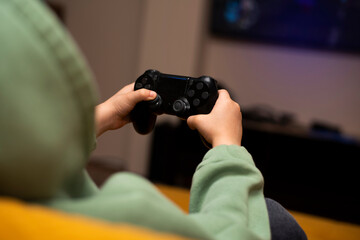 A little boy plays games on a game console with a black joystick © volkonskaya