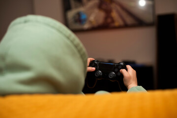 A little boy plays games on a game console with a black joystick © volkonskaya