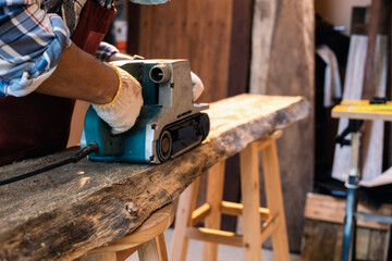 Using sanding machine belt sander to level surface wood. Carpenter use a hand-held electric sanding...
