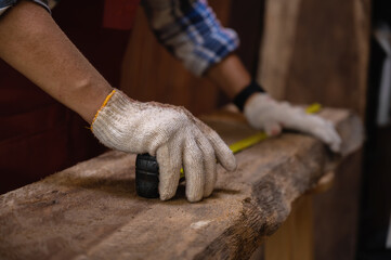 Carpenter use Measuring tape and pencil to marking on timber. Selective focus and close-up on hand to work.