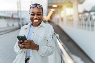 Cropped shot of a African American young woman waiting on station and using smart phone.