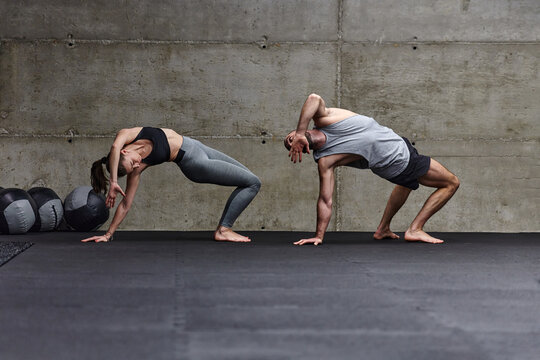 An attractive couple in the gym engaging in various stretching exercises together, showcasing their dedication to fitness, flexibility, and overall well-being. With synchronized movements, they