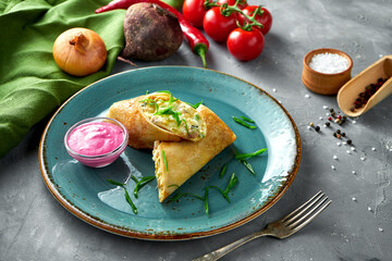 Pancake rolls stuffed with meat and sour cream in a clay bowl on a gray background. Blini, stuffed crepe