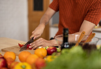 A homely and healthy male prepares nutritious diet, including variety of fruits. Following cooking show on laptop Mastery of peeling, chopping, and slicing fruits to prepare them in artistic style.