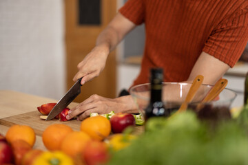 A homely and healthy male prepares nutritious diet, including variety of fruits. Following cooking show on laptop Mastery of peeling, chopping, and slicing fruits to prepare them in artistic style.