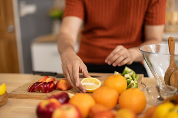 A homely and healthy male prepares nutritious diet, including variety of fruits. Following cooking show on laptop Mastery of peeling, chopping, and slicing fruits to prepare them in artistic style.