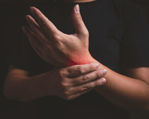 Close-up of man's arm holding his painful wrist caused by prolonged overwork. Carpal tunnel syndrome, rheumatism, neurological disease concept, hand numbness.