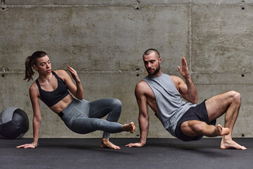 An attractive couple in the gym engaging in various stretching exercises together, showcasing their...