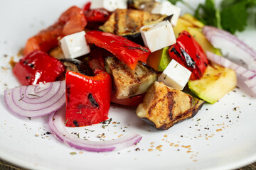 Greek salad, vegetables with cheese. Grilled vegetables eggplant, paprika, onions. Serving on a wooden Board on a rustic table. Barbecue restaurant menu