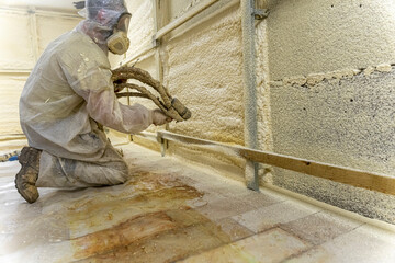 worker in a protective suit insulates the walls with polyurethane foam - obrazy, fototapety, plakaty