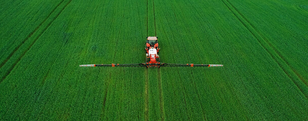 Aerial  view of tractor spraying pesticides on wheat  field with sprayer  in spring. © Miha Creative