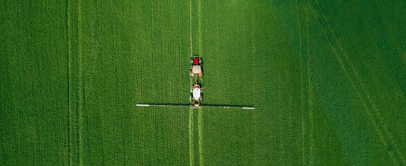 Aerial  view of tractor spraying pesticides on wheat  field with sprayer  in spring. © Miha Creative
