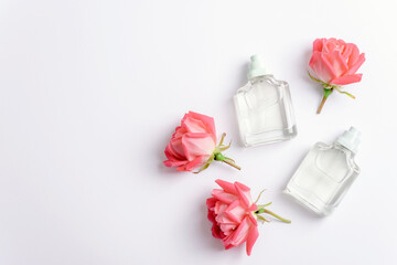 Two perfume bottles and rose flowers on white background. Beauty, fashion concept. Top view, flat lay, copy space