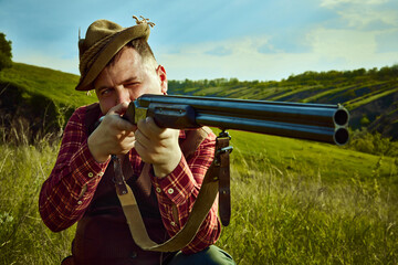 Close up portrait with man, hunter wearing vintage clothes and checked shirt shooting prey with a...