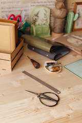 Creative Corner. Details on a wooden work table, scissors, thread, fabrics. 