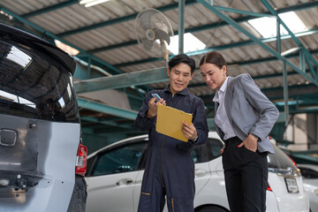 Fototapeta na wymiar Asian car mechanic man in uniform explaining checklist car maintenance and repair to woman client at auto car garage service