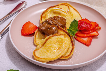 Cottage cheese pancakes, syrniki, curd fritters with strawberry, mint and powdered sugar on plate