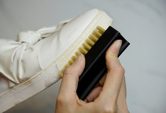 Cropped hand brushing a white shoe base