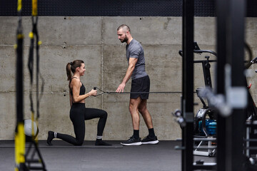 A muscular man assisting a fit woman in a modern gym as they engage in various body exercises and muscle stretches, showcasing their dedication to fitness and benefiting from teamwork and support