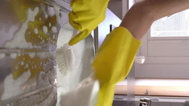 The housewife washes the dishes in the sink in the kitchen. Dolly shot.