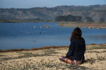 Mujer hermosa meditando a la orilla de una laguna