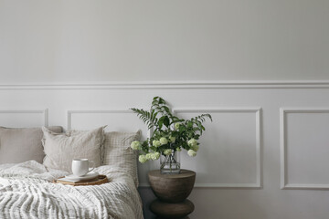 Breakfast in bed. Cup of coffee, wicker tray. Green bouquet of white viburnum, fern and solomons...