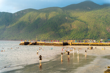 Tourists enjoying sea waves at famous Con Dao beach. Travel and landscape concept.