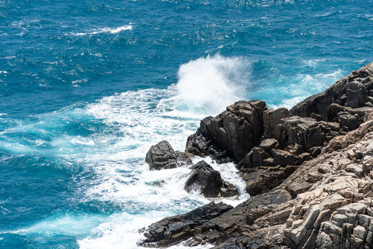 waves hit the rock at beach, sea water splash up to the sky with sun. A peaceful Con Dao island, Vietnam is a Vietnamese island heaven
