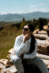 Fototapeta premium Pretty woman in a white shirt and glasses posing against the backdrop of a modern mountain hotel.Businessman woman concept