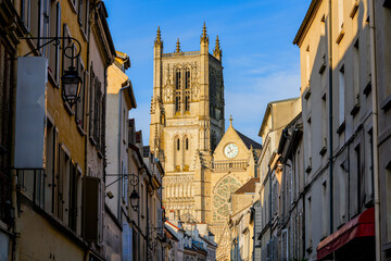 Fototapeta na wymiar Saint Etienne Cathedral of Meaux in the sun, as seen at the end of a dark narrow shopping street in the department of Seine et Marne near Paris, France
