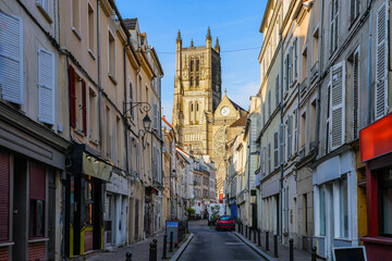 Saint Etienne Cathedral of Meaux in the sun, as seen at the end of a dark narrow shopping street in...
