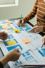 Frontend developer team brainstorms UI and UX design ideas for mobile apps on paper wireframe...