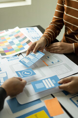 Frontend developer team brainstorms UI and UX design ideas for mobile apps on paper wireframe...