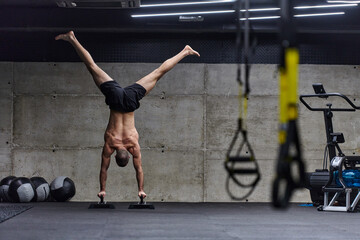 Fototapeta na wymiar A muscular man in a handstand position, showcasing his exceptional balance and body control while performing a variety of exercises to enhance his overall body stability and strength in a modern gym