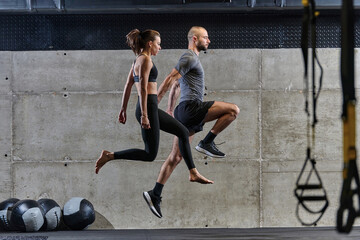 A fit couple exercising various types of jumps in a modern gym, demonstrating their physical fitness, strength, and athletic performance