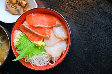 Premium fresh raw seafood mixed rice bowl (Kaisen-don, Japanese tasty food), Japanese Rice with sashimi of Salmon and Hotate on wood background