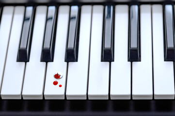 Drops of blood on the piano keyboard close up. Pushpin on the la key. The concept of sacrifice and...