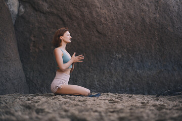 Woman doing yoga practice and meditating on the beach