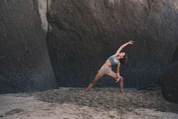 Woman is practicing yoga on the beach.