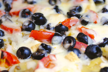 Homemade pizza with mozzarella cheese, tomatoes, olives, and mushrooms close-up food background texture. Cooking at home concept.