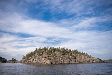 Obraz premium Rocky rocks in the lake on the background of a blue sky with clouds