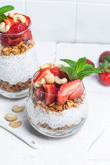 Granola with yogurt, chia and strawberries in a glass on a white background