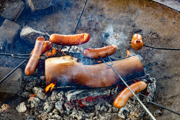 Frying sausages outdoors on a campfire