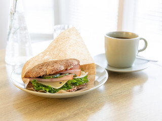 Sandwich with ham, cheese, vegetables and a cup of coffee