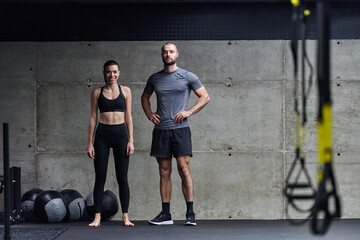 Fototapeta na wymiar Muscular man and fit woman in a conversation before commencing their training session in a modern gym.