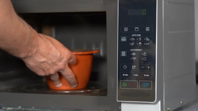 cooking and heating food for lunch and dinner with microwave at home and at work - hand takes heated food ready to use