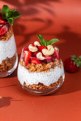 Granola with yogurt, chia and strawberries in a glass on a bright background