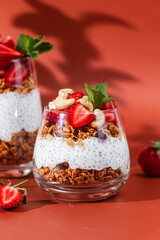 Granola with yogurt, chia and strawberries in a glass on a bright background