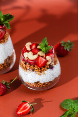 Granola with yogurt, chia and strawberries in a glass on a bright background